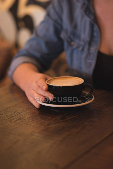 Mid section of woman having coffee at table in cafe — Stock Photo