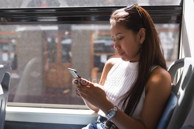Дівчина-підліток за допомогою мобільного телефону в автобусі — стокове фото