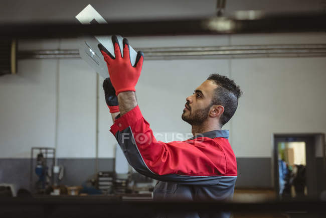 Ein männlicher Arbeiter überprüft in der Fabrik ein Maschinenbrett — Stockfoto