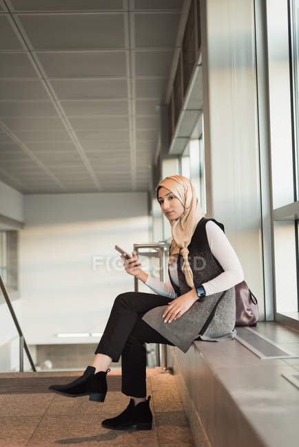 Mujer joven en hijab usando teléfono móvil - foto de stock