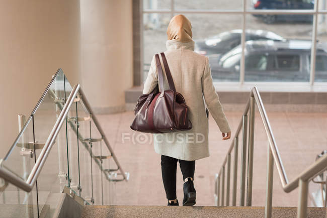 Вид сзади на женщину в хиджабе, спускающуюся с лестницы — стоковое фото