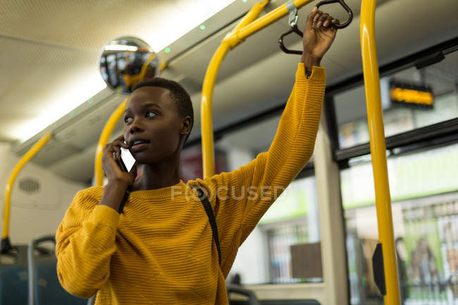 Mujer joven hablando por teléfono móvil mientras viaja en autobús - foto de stock
