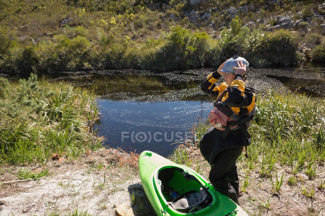 Mujer de pie con bote de kayak en la orilla del río . - foto de stock