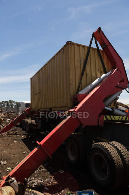 Кран крупним планом піднімає важкий контейнер на металобрухті — стокове фото