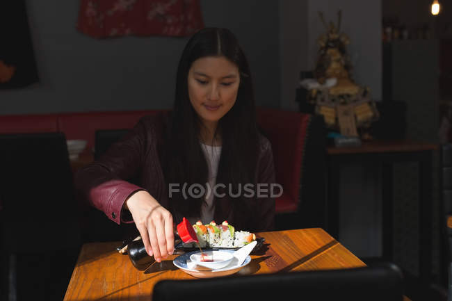 Jeune femme ayant de la nourriture sushi au restaurant — Photo de stock