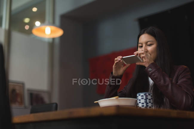 Жінка фотографує їжу з мобільним телефоном в ресторані — стокове фото