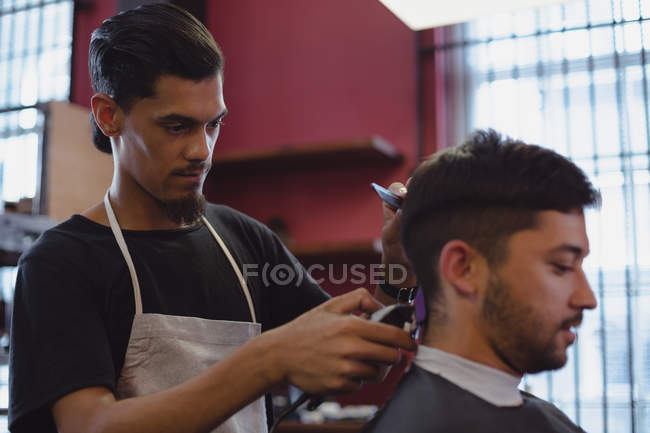Homme se faire couper les cheveux avec tondeuse au salon de coiffure — Photo de stock
