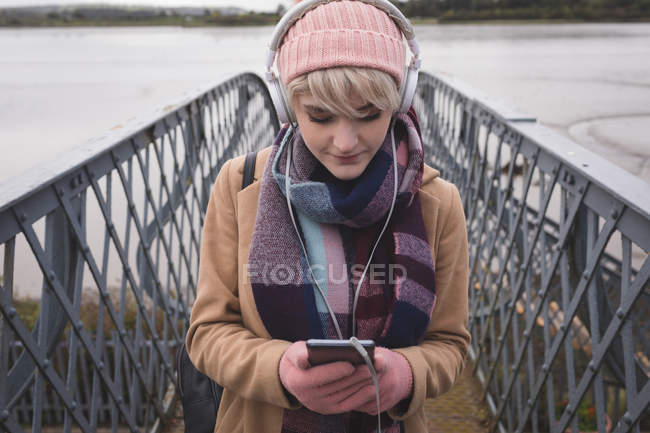 Woman listening to music on mobile phone in bridge — Stock Photo