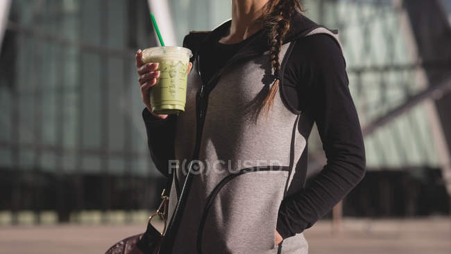 Mid section of woman having drink on street — Stock Photo
