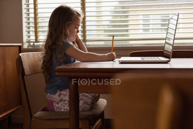 Чарівна маленька дівчинка робить домашнє завдання вдома — стокове фото