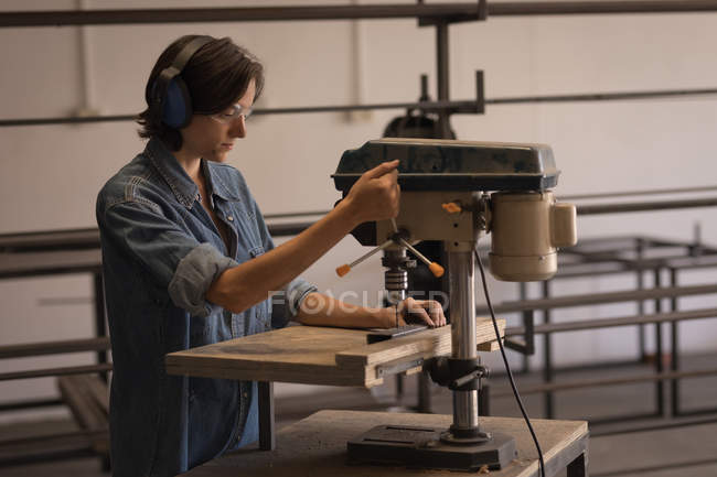 Female artisan using vertical drilling machine in workshop. — Stock Photo