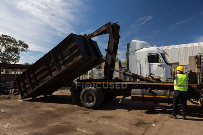Вид ззаду працівника, що піднімає контейнер вантажівки-носія — стокове фото