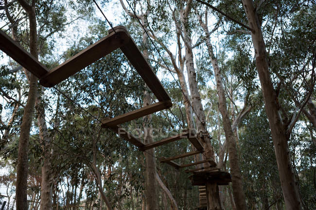 Visão de baixo ângulo de obstáculos de madeira do curso de cordas na floresta — Fotografia de Stock