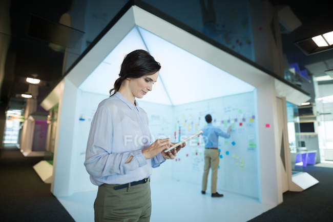 Femme exécutive utilisant une tablette numérique dans un bureau futuriste . — Photo de stock
