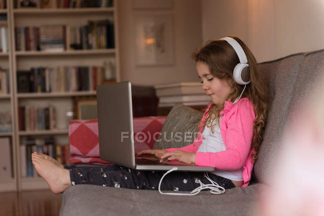 Mädchen benutzt Laptop auf Sofa im Wohnzimmer zu Hause — Stockfoto