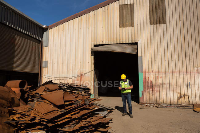Worker using digital tablet at scrapyard on a sunny day — Stock Photo