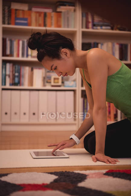 Femme utilisant une tablette numérique dans le salon à la maison — Photo de stock