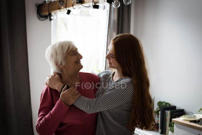 Бабушка и внучка обнимаются в гостиной дома — стоковое фото