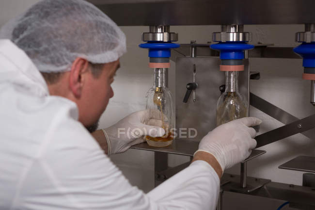 Homme travailleur remplir gin dans les bouteilles à l'usine — Photo de stock