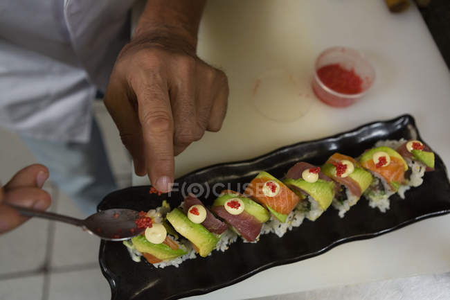 Primer plano del chef organizando sushi en una bandeja en el restaurante - foto de stock