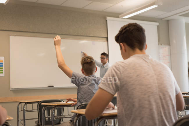 Estudiante universitario levantando la mano en el aula en la universidad - foto de stock