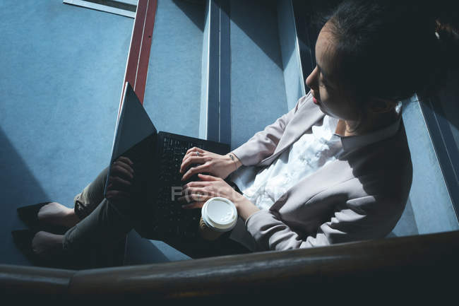 Женщина-руководитель использует ноутбук на лестнице в офисе — стоковое фото