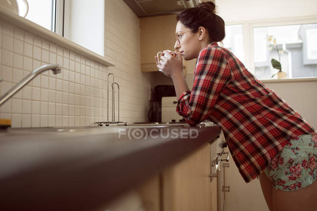 Mujer bebiendo café en la cocina en casa, vista de bajo ángulo . - foto de stock