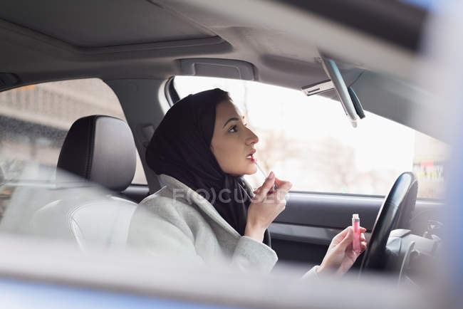 Jovem mulher em hijab aplicando batom — Fotografia de Stock
