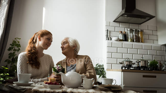 Avó e neta olhando um para o outro na sala de estar em casa — Fotografia de Stock