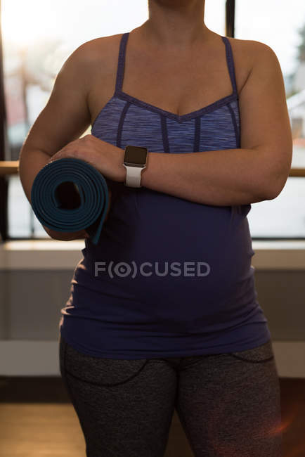 Mid section of pregnant woman holding a exercise mat at home — Stock Photo