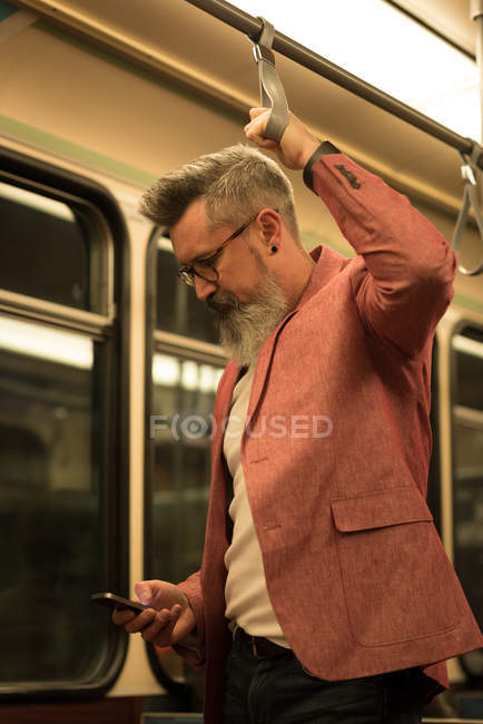 Чоловік стоїть за допомогою мобільного телефону під час подорожі в поїзді — стокове фото