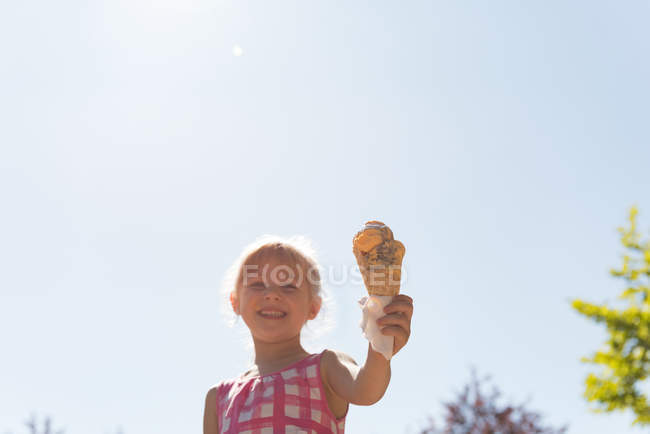 Chica feliz sosteniendo helado con doble cuchara en un día soleado - foto de stock