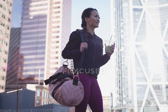 Fit woman having drink after workout against building — Stock Photo