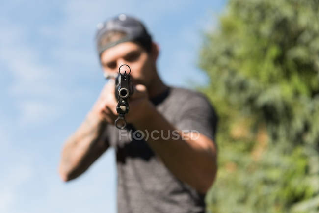 Homme tirant avec une arme par une journée ensoleillée — Photo de stock