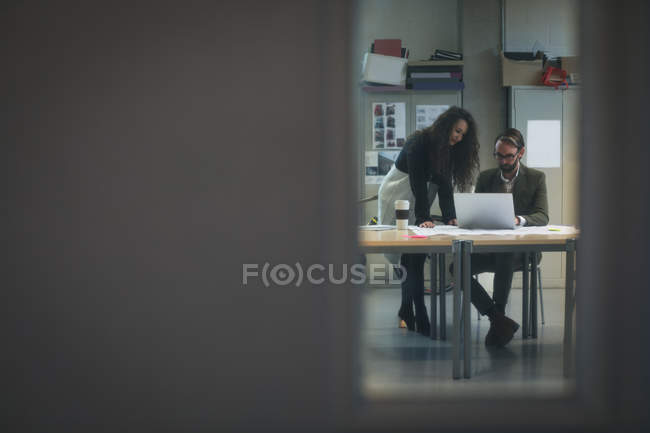 Dirigeants discutant sur ordinateur portable dans le bureau moderne — Photo de stock