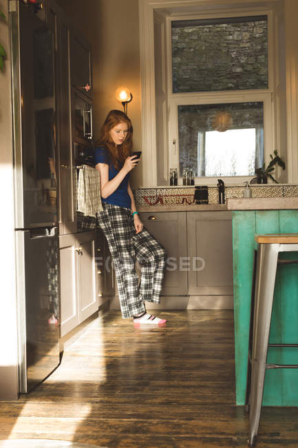 Frau benutzt Handy in Küche zu Hause — Stockfoto