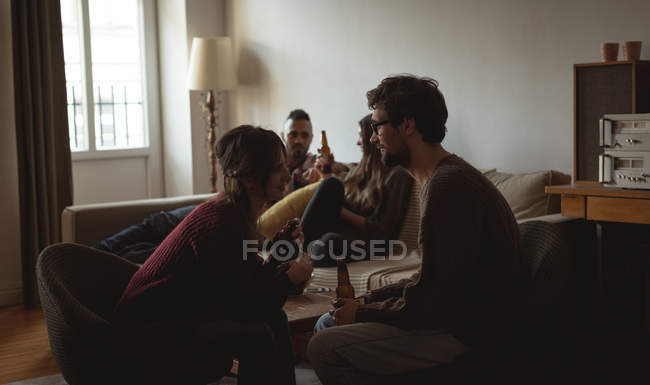 Friends having beer in living room at home — Stock Photo