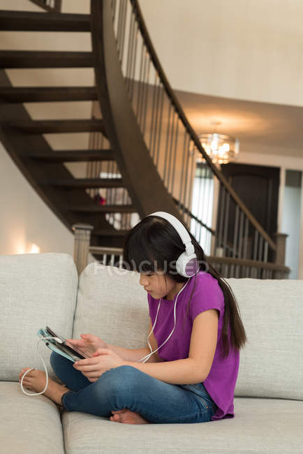 Femme avec écouteurs utilisant une tablette numérique à la maison — Photo de stock