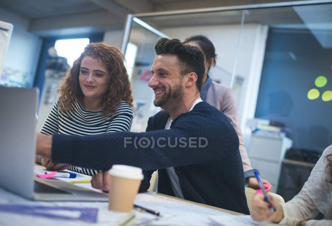 Dirigenti sorridenti discutono sopra computer portatile in ufficio — Foto stock