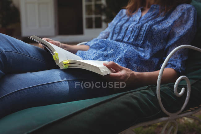 Mid section of woman reading book on armchair — Stock Photo