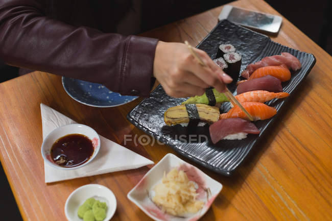 Крупним планом жінка з суші їжею в ресторані — стокове фото