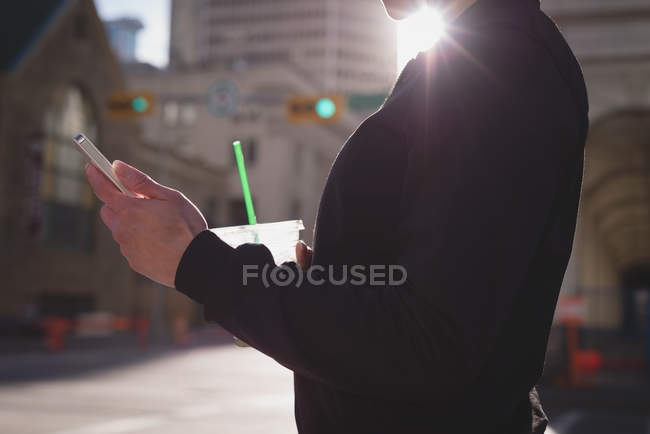 Mid section of woman using mobile phone while having drink on street — Stock Photo