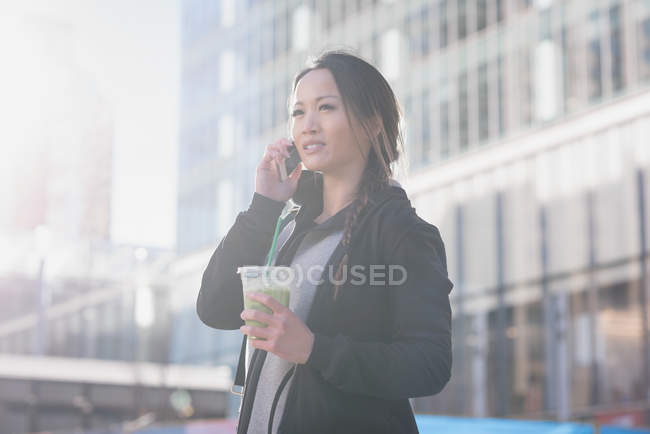 Mujer tomando el teléfono móvil mientras toma una copa - foto de stock