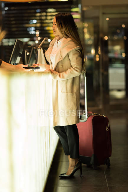 Empresaria de pie en recepción con su equipaje en el hotel - foto de stock