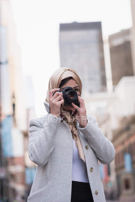Jeune femme en hijab en cliquant sur les photos avec appareil photo numérique — Photo de stock