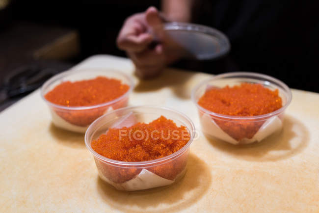 Chef embalando ovos de peixe em um recipiente no restaurante — Fotografia de Stock