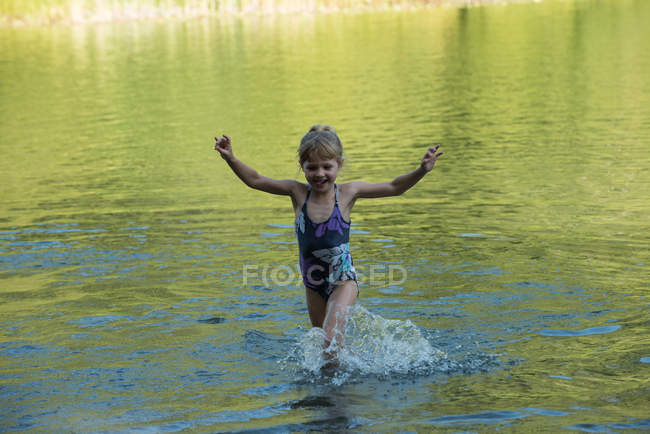 Chica jugando en el río en un día soleado - foto de stock