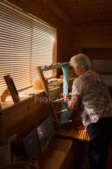 Aktive Seniorin webt Seide im Geschäft — Stockfoto
