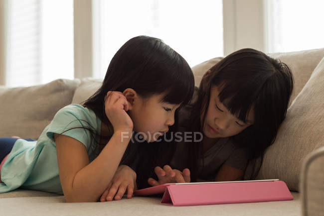 Fratelli e sorelle che utilizzano tablet digitale in soggiorno a casa — Foto stock