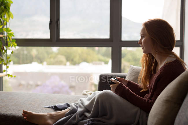 Jeune femme jouant à des jeux vidéo à la maison — Photo de stock
